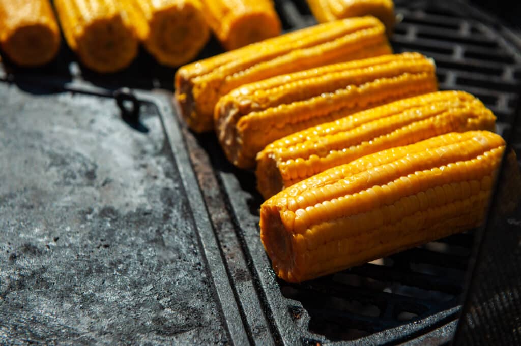 A professional cook prepares corn on the grill outdoor, food or catering concept
